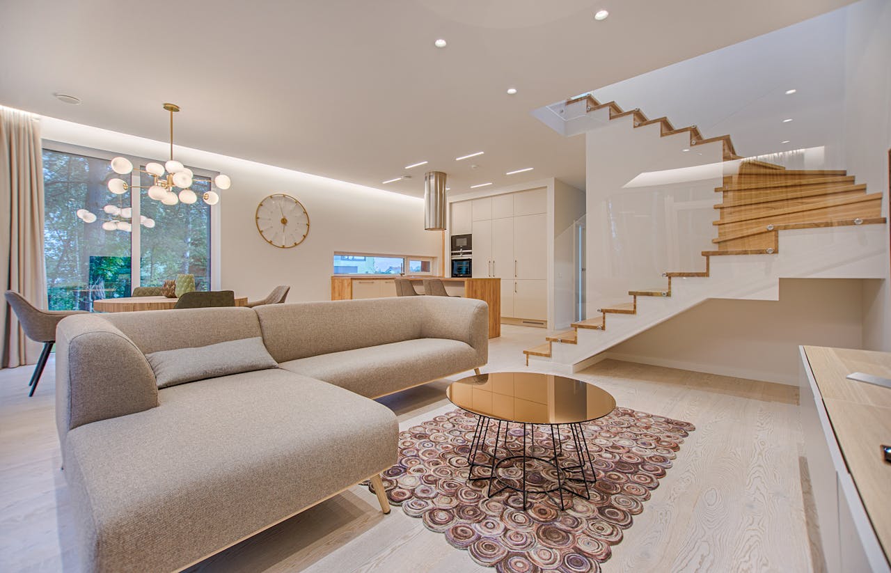 heros-img Contemporary living room with neutral tones, a sleek sofa, and elegant wooden staircase.