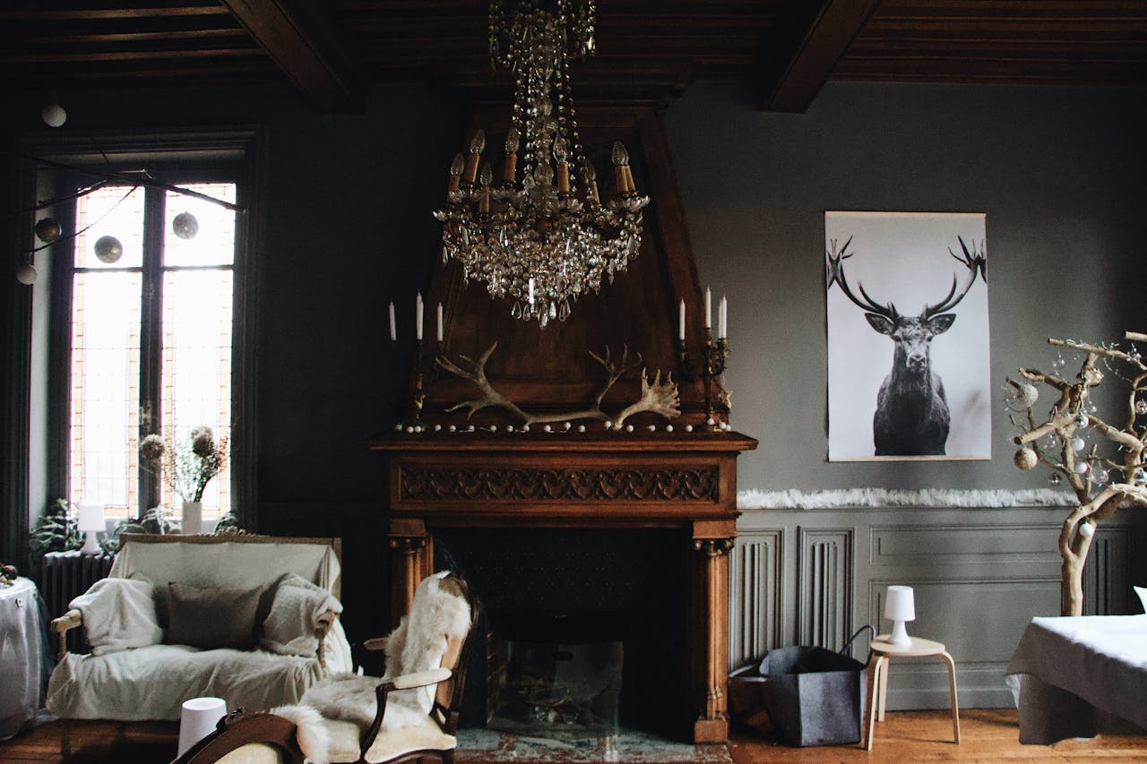 A cozy living room featuring vintage decor with a chandelier, fireplace, and antlers.